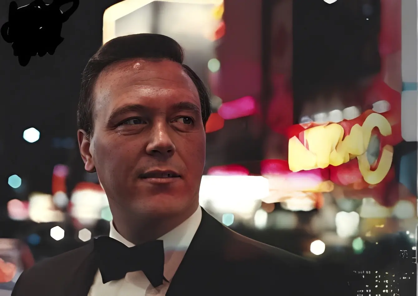 Man in tuxedo with city lights background.