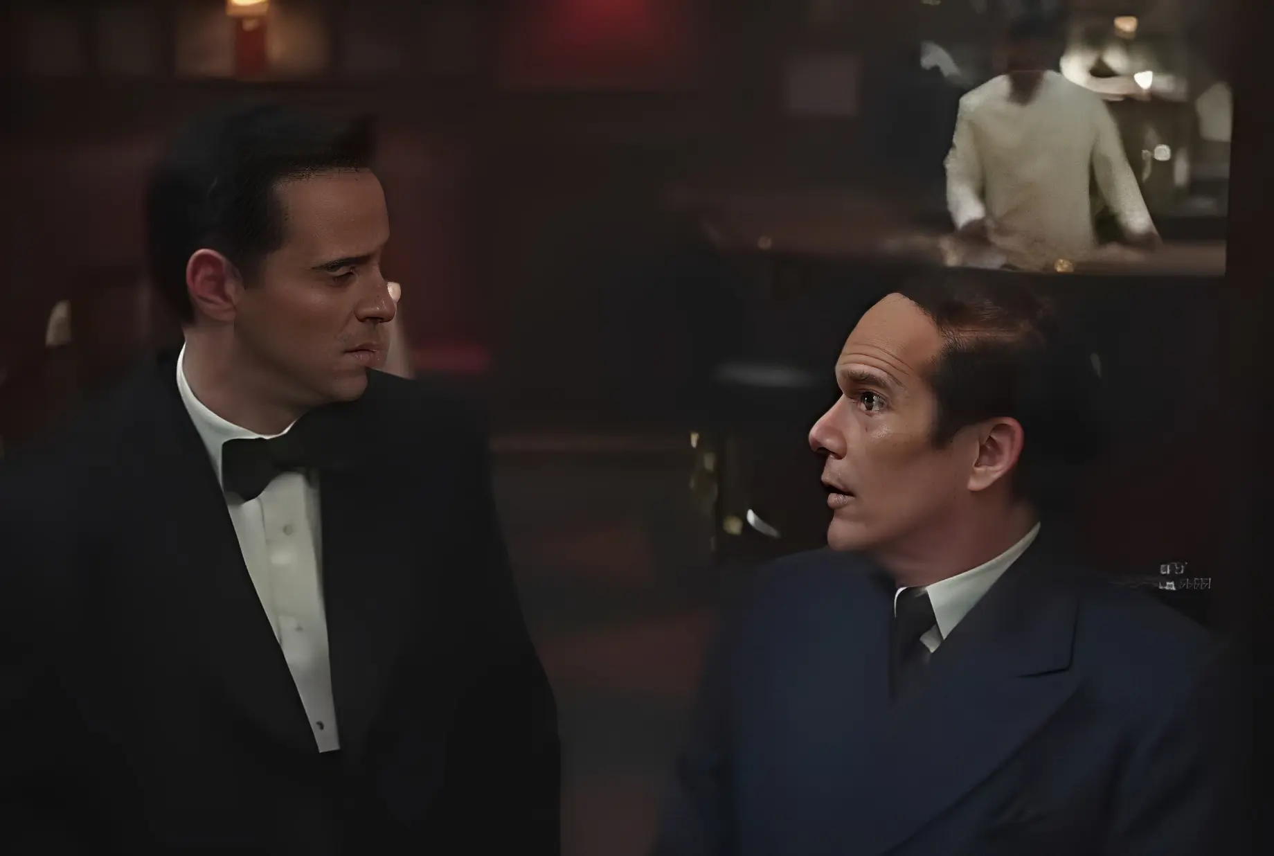 Two men talking in a dimly lit room.