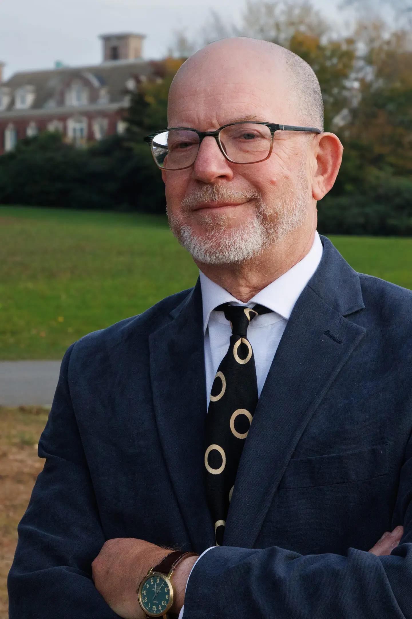 Smiling older man in glasses and suit outdoors.